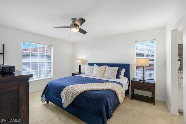 bedroom with multiple windows, ceiling fan, and light carpet