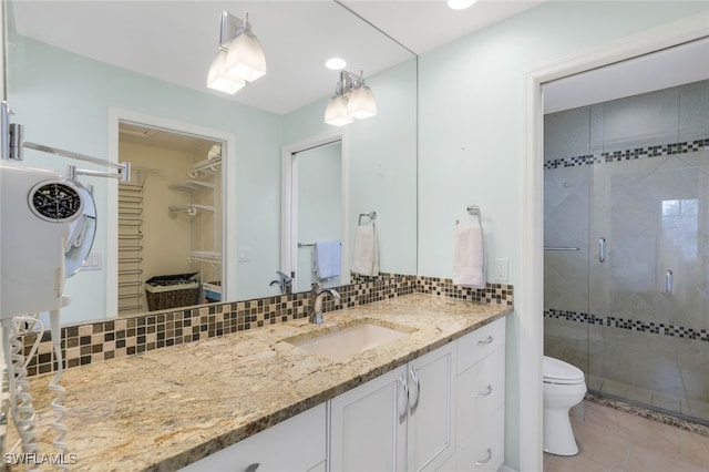 bathroom featuring tasteful backsplash, tile patterned floors, an enclosed shower, vanity, and toilet