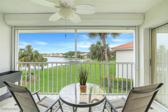 sunroom with ceiling fan and a water view