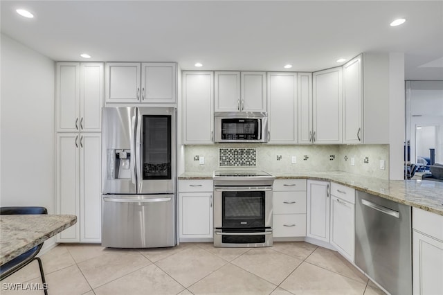 kitchen with stainless steel appliances, white cabinetry, tasteful backsplash, and light tile patterned flooring