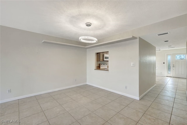 tiled spare room featuring a textured ceiling and an inviting chandelier