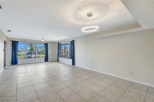 spare room with a textured ceiling, light tile patterned flooring, and ceiling fan with notable chandelier