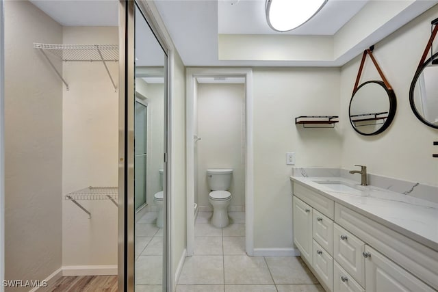 bathroom featuring tile patterned floors, vanity, toilet, and a shower with door