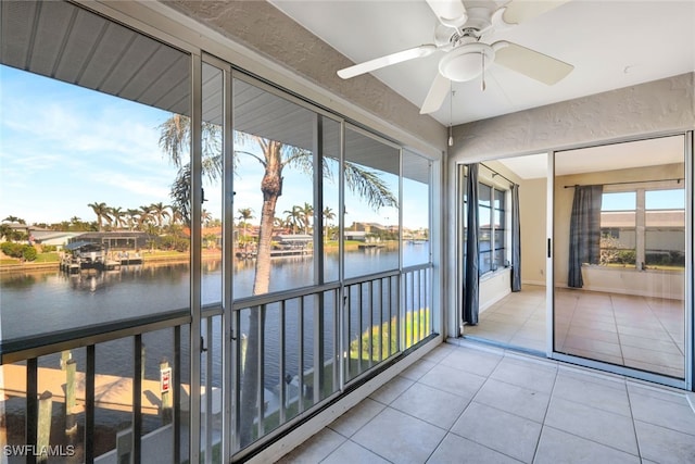 unfurnished sunroom with ceiling fan and a water view