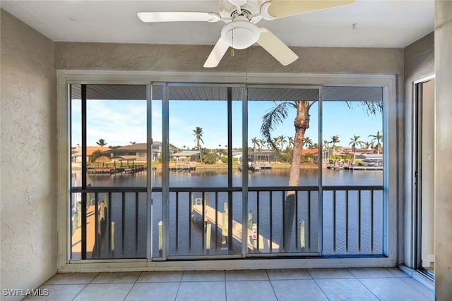 unfurnished sunroom with ceiling fan, a healthy amount of sunlight, and a water view