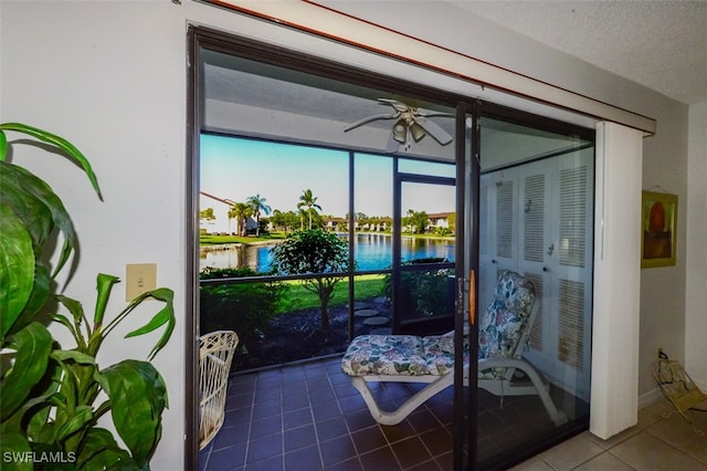 interior space featuring tile patterned flooring, a textured ceiling, a water view, and ceiling fan