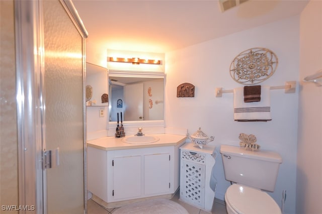 bathroom with tile patterned flooring, vanity, an enclosed shower, and toilet