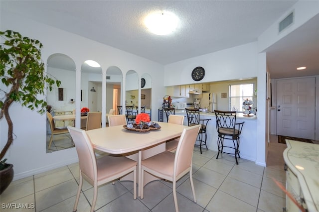 dining area featuring a textured ceiling and light tile patterned flooring