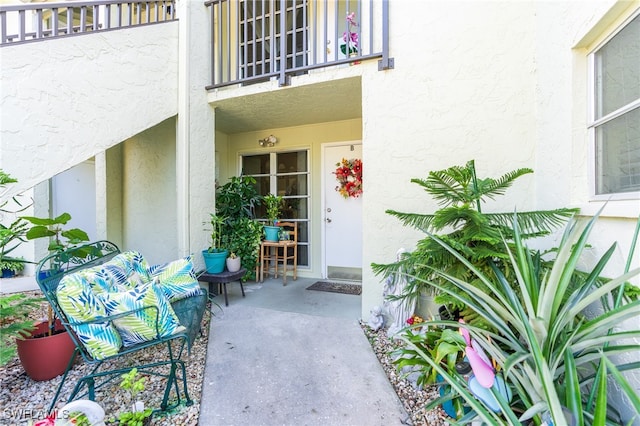 view of exterior entry featuring a balcony and a patio