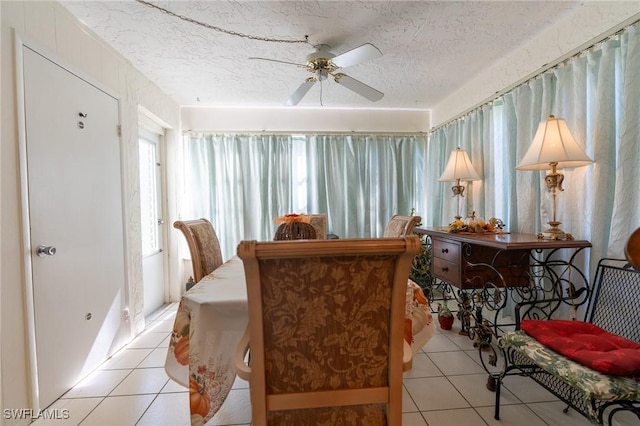 tiled dining room with ceiling fan and a textured ceiling