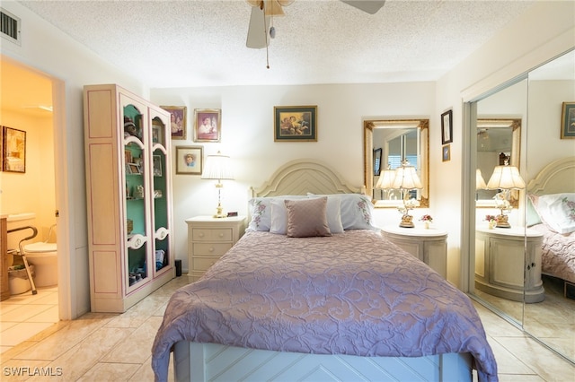 bedroom featuring ceiling fan, a closet, light tile patterned floors, and a textured ceiling