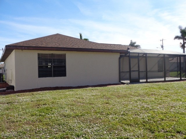 view of side of home featuring a yard and glass enclosure