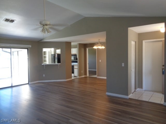 unfurnished living room featuring ceiling fan with notable chandelier, dark hardwood / wood-style flooring, and lofted ceiling