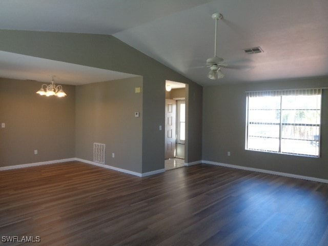 empty room with ceiling fan with notable chandelier, dark hardwood / wood-style flooring, and vaulted ceiling