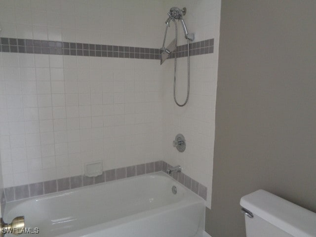 bathroom with tiled shower / bath combo and toilet