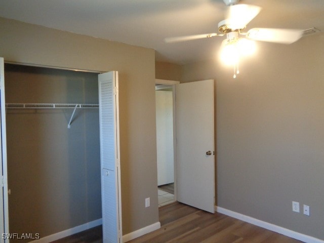 unfurnished bedroom with ceiling fan, a closet, and wood-type flooring