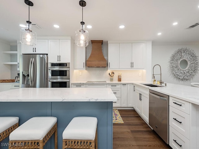 kitchen featuring appliances with stainless steel finishes, custom range hood, sink, pendant lighting, and white cabinets