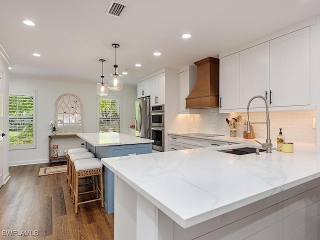 kitchen featuring a wealth of natural light, sink, a kitchen island, and custom range hood