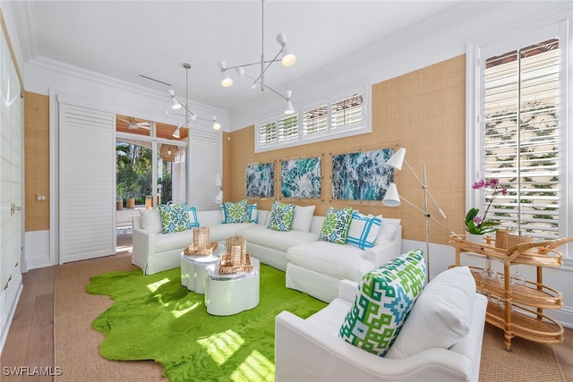 living room featuring wood-type flooring, crown molding, and a notable chandelier