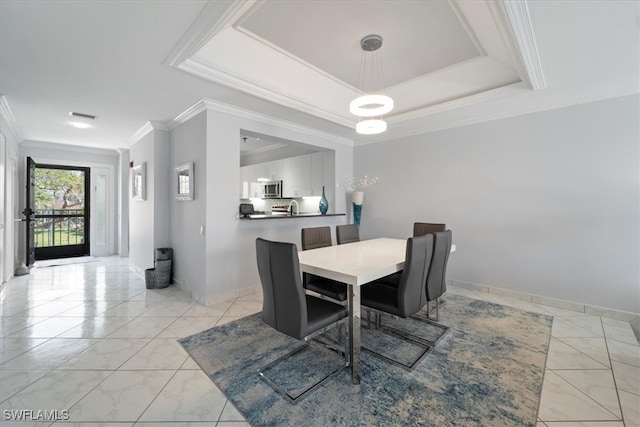 dining room with a raised ceiling, ornamental molding, and sink