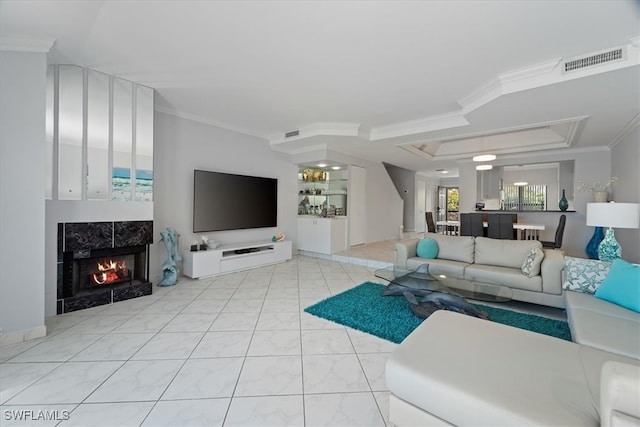 living room with a tile fireplace and ornamental molding