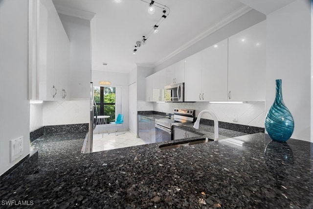 kitchen featuring ornamental molding, stainless steel appliances, white cabinetry, and dark stone counters