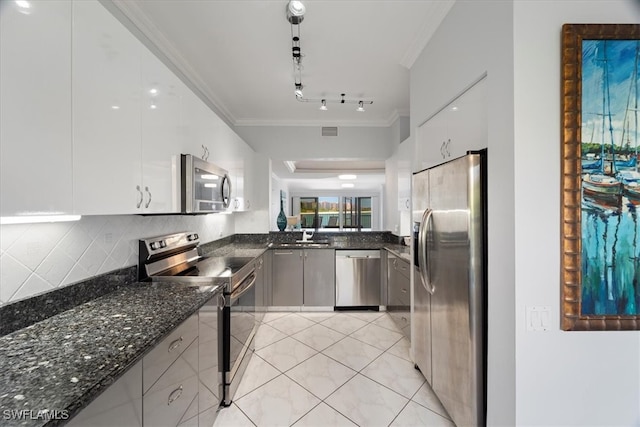 kitchen with dark stone counters, white cabinetry, crown molding, and stainless steel appliances