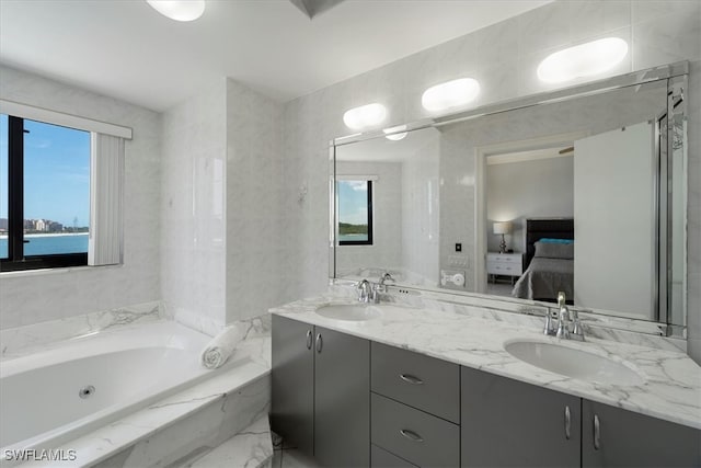 bathroom featuring plenty of natural light, tiled tub, a water view, and vanity