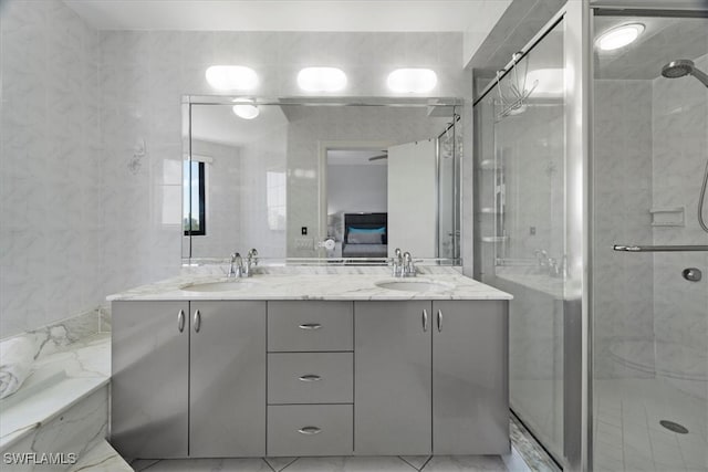 bathroom with vanity, a shower with door, and tile walls