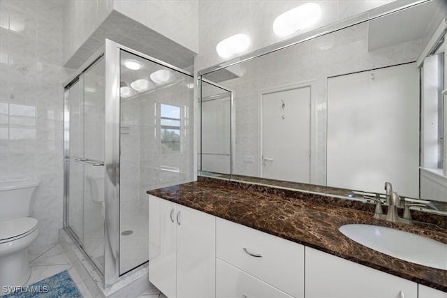 bathroom with vanity, toilet, an enclosed shower, and tile walls