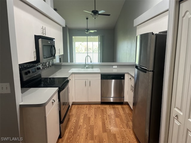 kitchen featuring appliances with stainless steel finishes, light wood-type flooring, sink, white cabinetry, and lofted ceiling