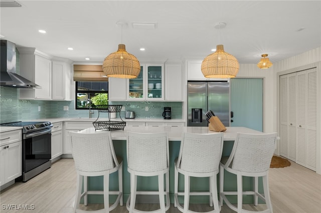 kitchen with pendant lighting, a center island, stainless steel appliances, and wall chimney exhaust hood