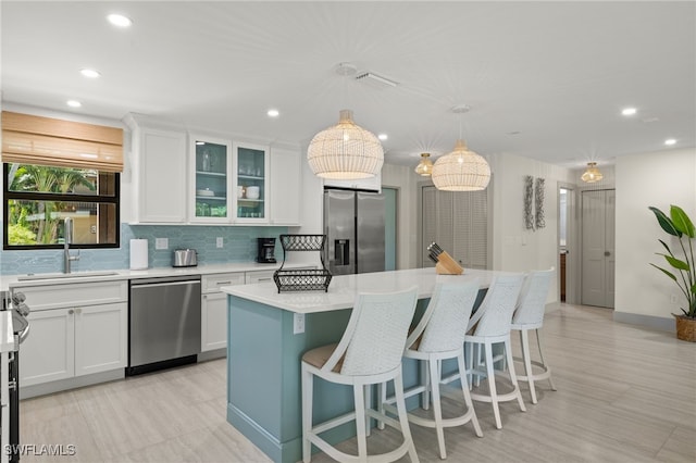 kitchen with white cabinetry, sink, a center island, pendant lighting, and appliances with stainless steel finishes