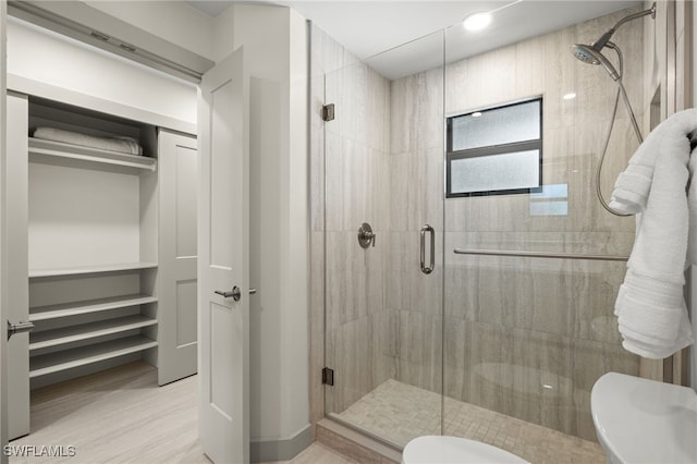 bathroom with walk in shower, hardwood / wood-style floors, and toilet