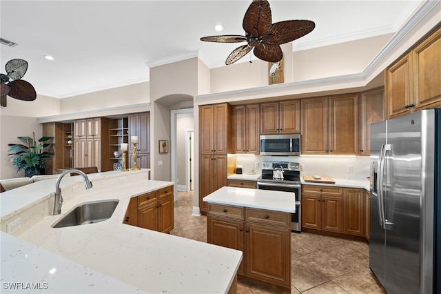 kitchen with sink, a kitchen island, ornamental molding, and appliances with stainless steel finishes