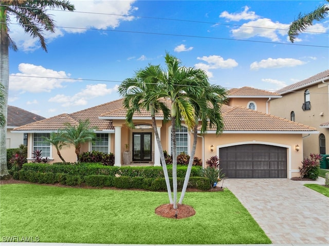 mediterranean / spanish-style house featuring french doors, a front lawn, and a garage