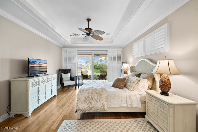 bedroom with access to exterior, ceiling fan, light hardwood / wood-style flooring, a tray ceiling, and ornamental molding