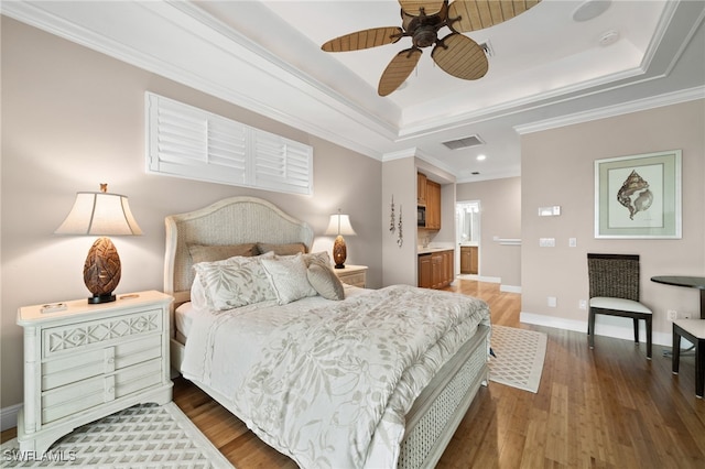 bedroom with ornamental molding, a raised ceiling, ceiling fan, dark wood-type flooring, and connected bathroom