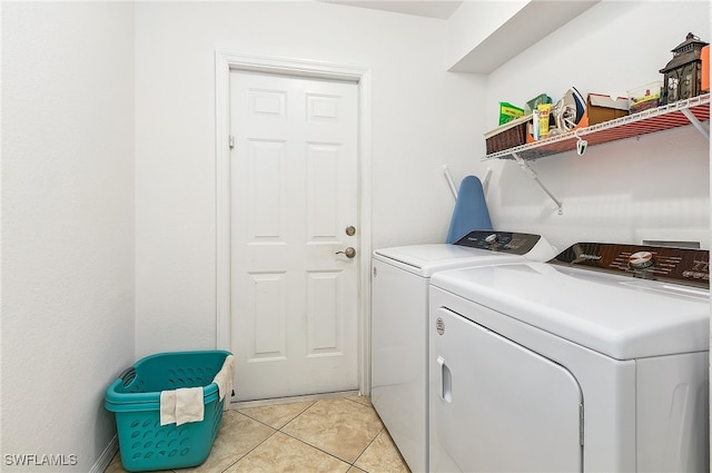 clothes washing area with light tile patterned floors and washer and clothes dryer