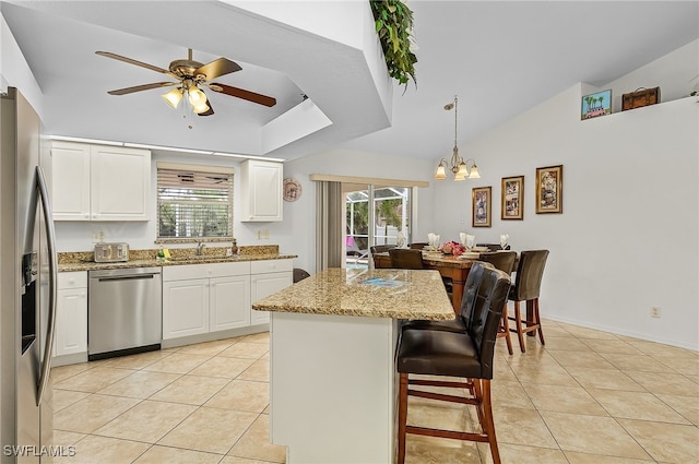 kitchen featuring hanging light fixtures, light stone countertops, white cabinets, and appliances with stainless steel finishes