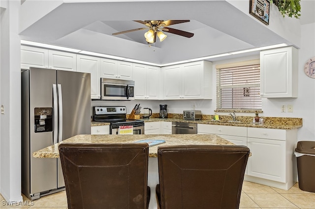 kitchen featuring stainless steel appliances, white cabinetry, a kitchen island, and light tile patterned floors