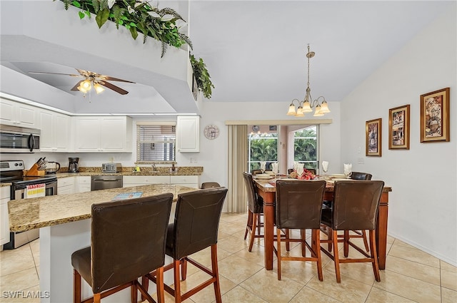 dining space with light tile patterned flooring, lofted ceiling, sink, and ceiling fan with notable chandelier