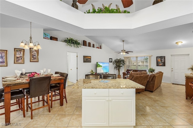 kitchen featuring light tile patterned flooring, high vaulted ceiling, hanging light fixtures, a kitchen island, and white cabinets