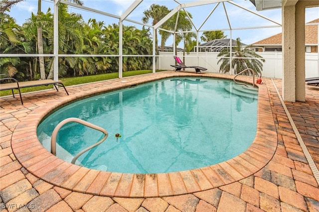 view of pool with glass enclosure and a patio area