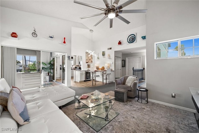 living room with wine cooler, ceiling fan, carpet flooring, and high vaulted ceiling