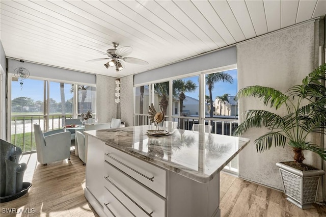 interior space featuring a water view, wood ceiling, light hardwood / wood-style flooring, a kitchen island, and ceiling fan