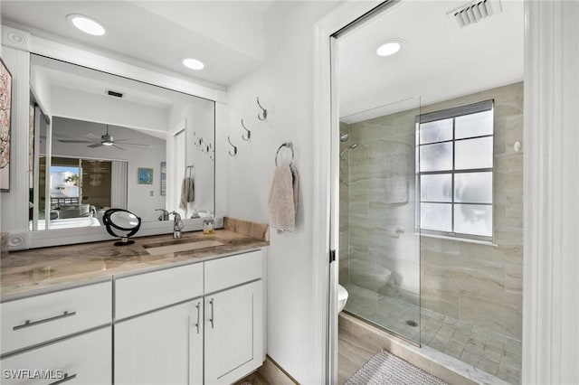 bathroom with vanity, ceiling fan, a shower with shower door, and toilet