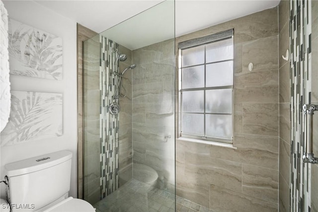 bathroom featuring tiled shower and toilet