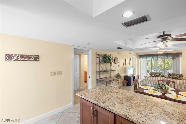 kitchen featuring light stone countertops, ceiling fan, and light tile patterned flooring