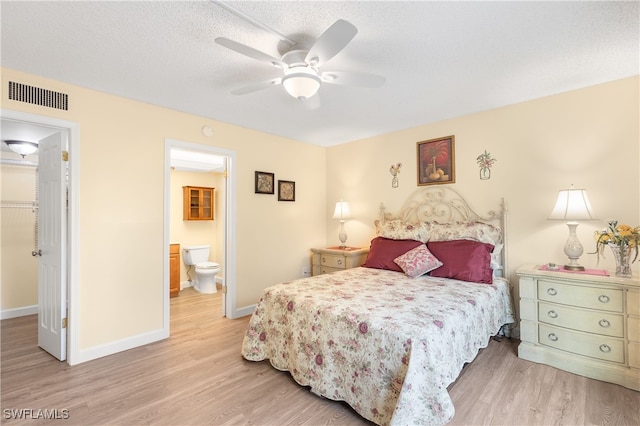 bedroom with ensuite bathroom, ceiling fan, a textured ceiling, and light wood-type flooring